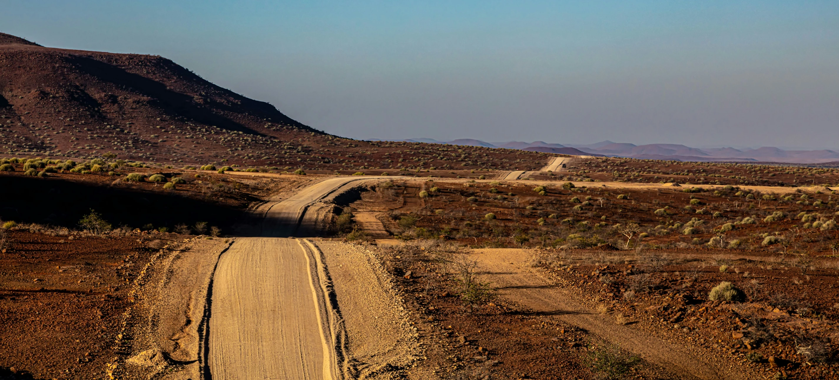 there is a dirt road going through a desert area