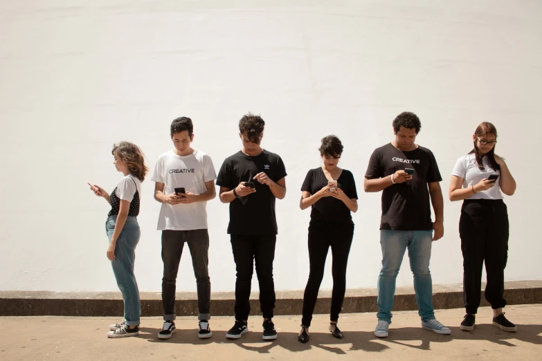 six people standing together, all using their cellphones