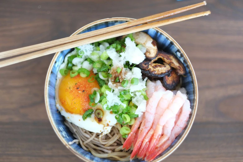 a blue bowl of food that includes noodles, meats and vegetables
