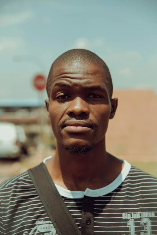 man with a striped shirt on and bag around his neck