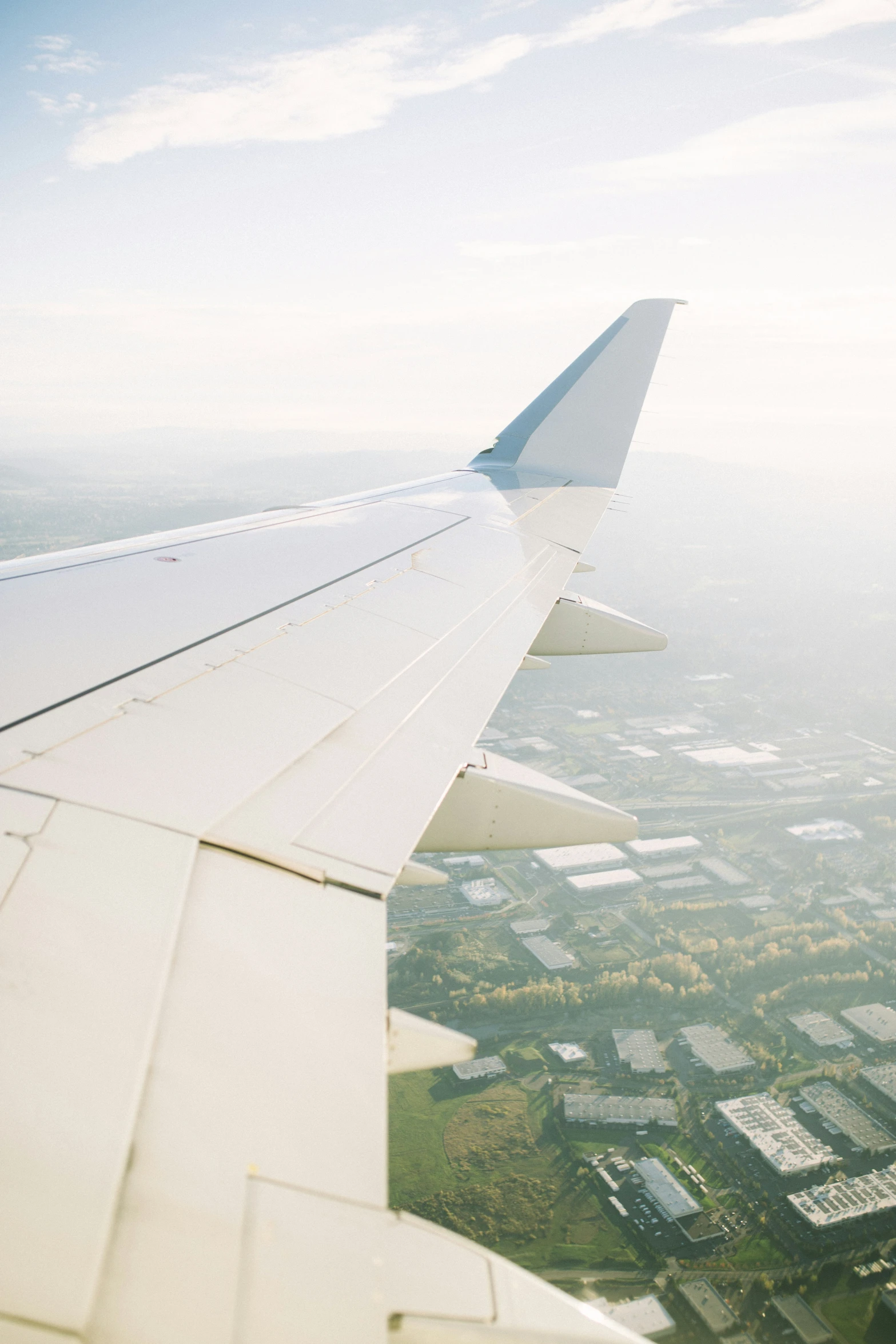 the view out an airplane window shows a wing and the landscape