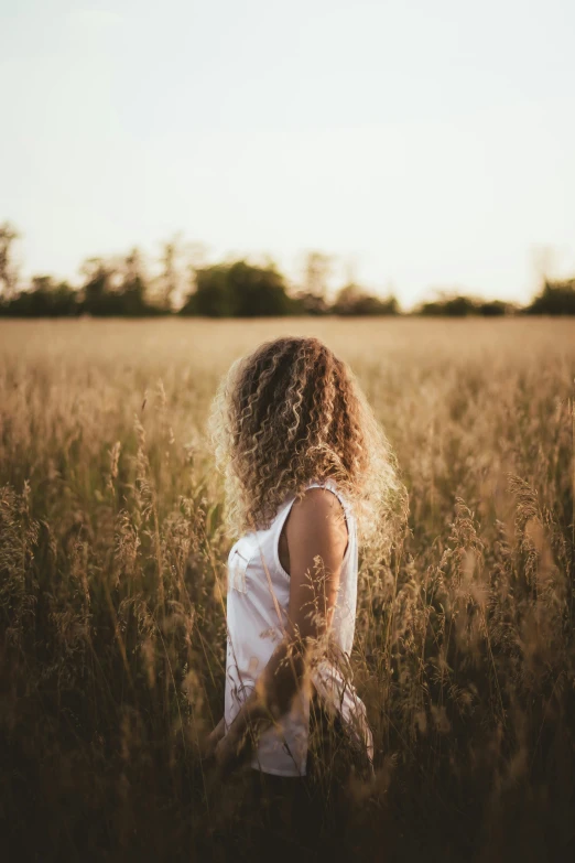 young woman in large field of grass with blonde hair