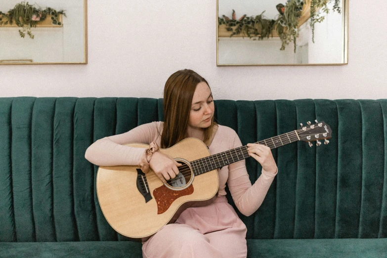 a person playing a guitar on a green couch