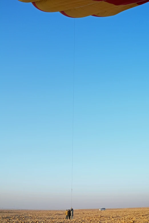 two men fly a large kite over the desert