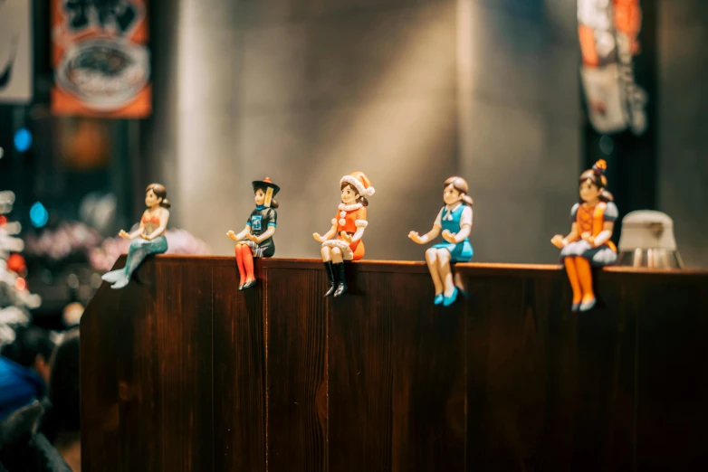 figurines of people sitting on top of a wooden fence