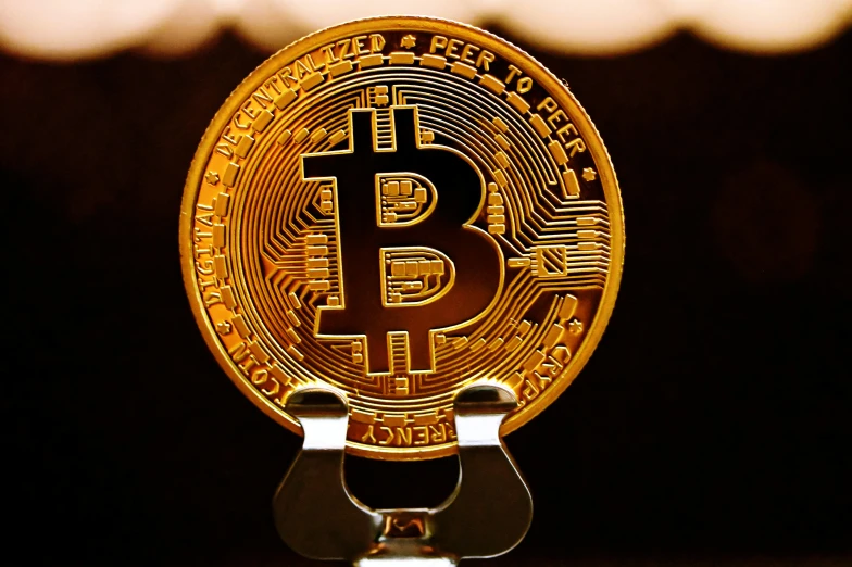 a gold bitcoin sits on top of the metal plate