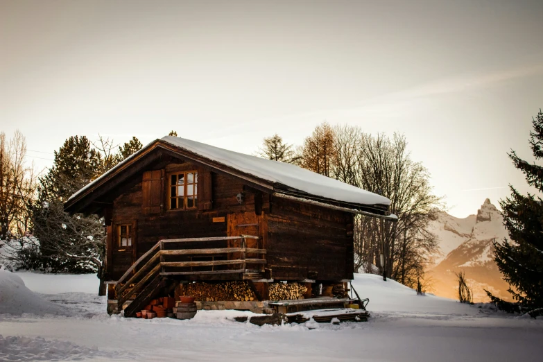 an old cabin sits next to snow covered pine trees