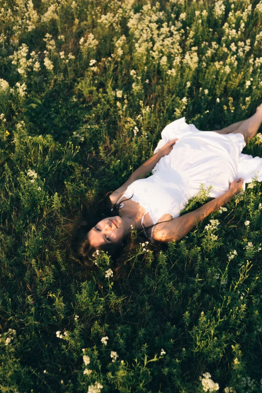 the man in the white shirt is lying on his back in a field of flowers
