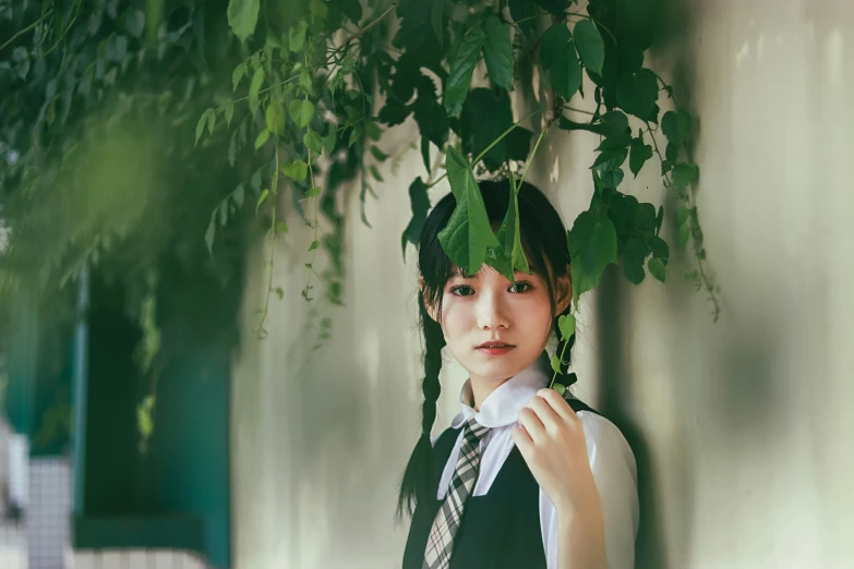 a woman in a dress and tie standing near a tree