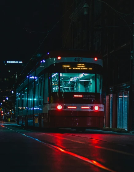 a bus on the street at night with some red light