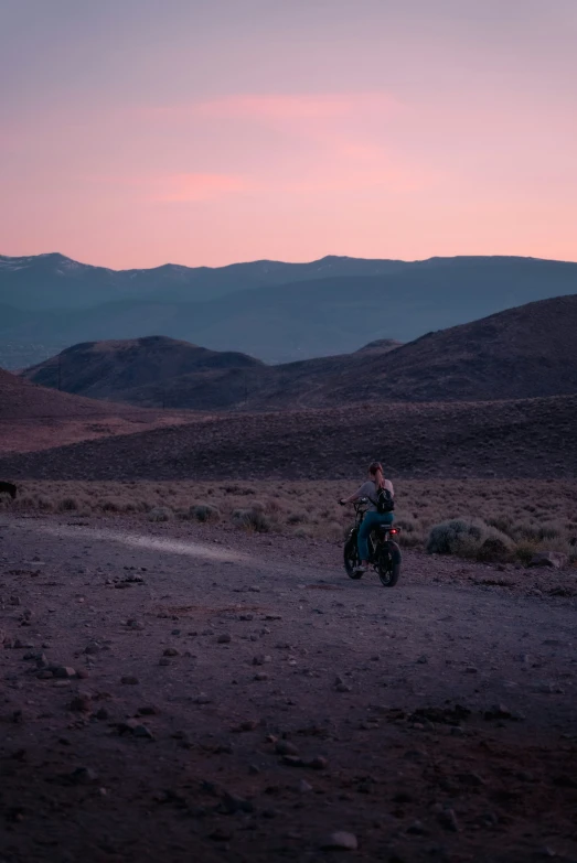 the man is sitting on his motorcycle on the dirt road