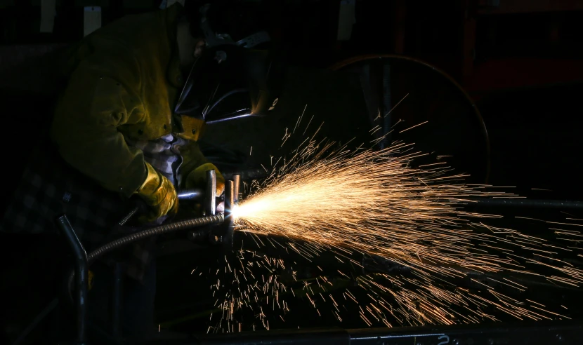 a man in yellow coat spraying sparks in air