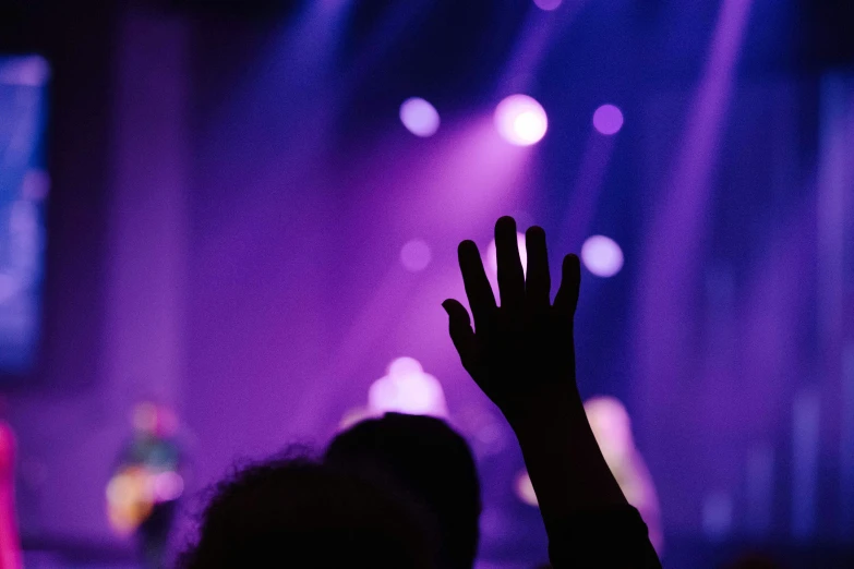 a silhouette of a person raising their hands during a performance