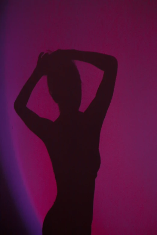 woman posing with her arms up against a neon background