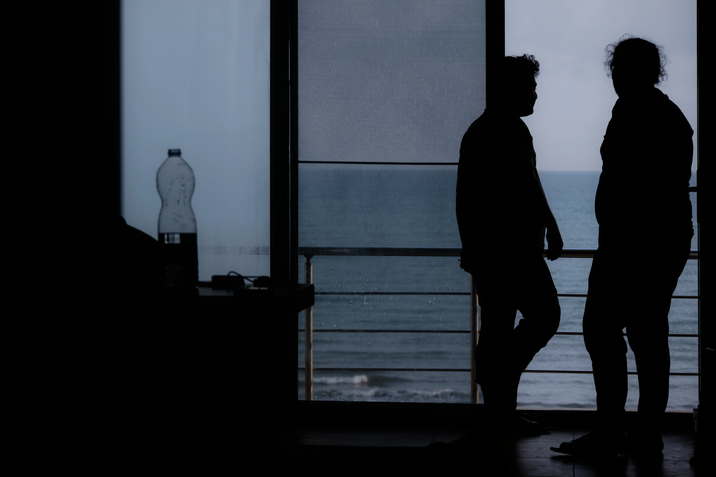 two men are talking while standing near some glass doors