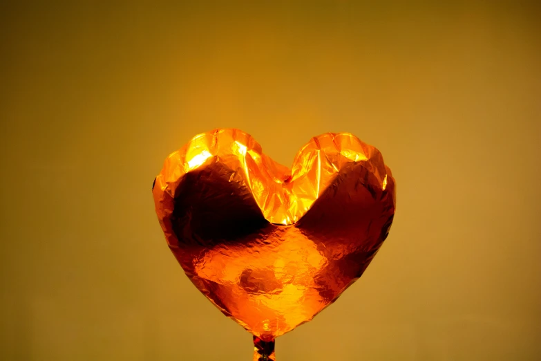 an orange piece of heart shaped candy is being held in someone's hand