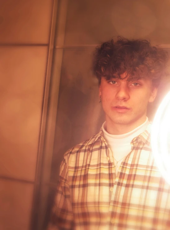 man with plaid shirt and hair in front of mirror