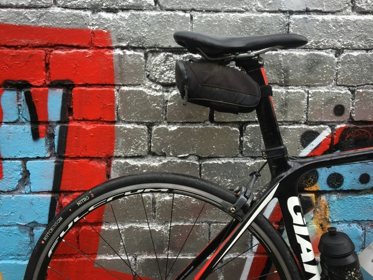 a bicycle against a wall with graffiti and a red, blue, yellow and white sign