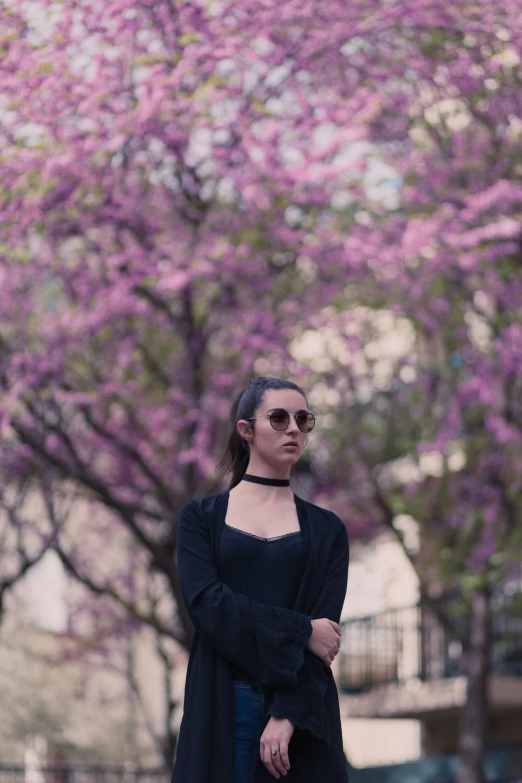 a woman standing in front of pink tree