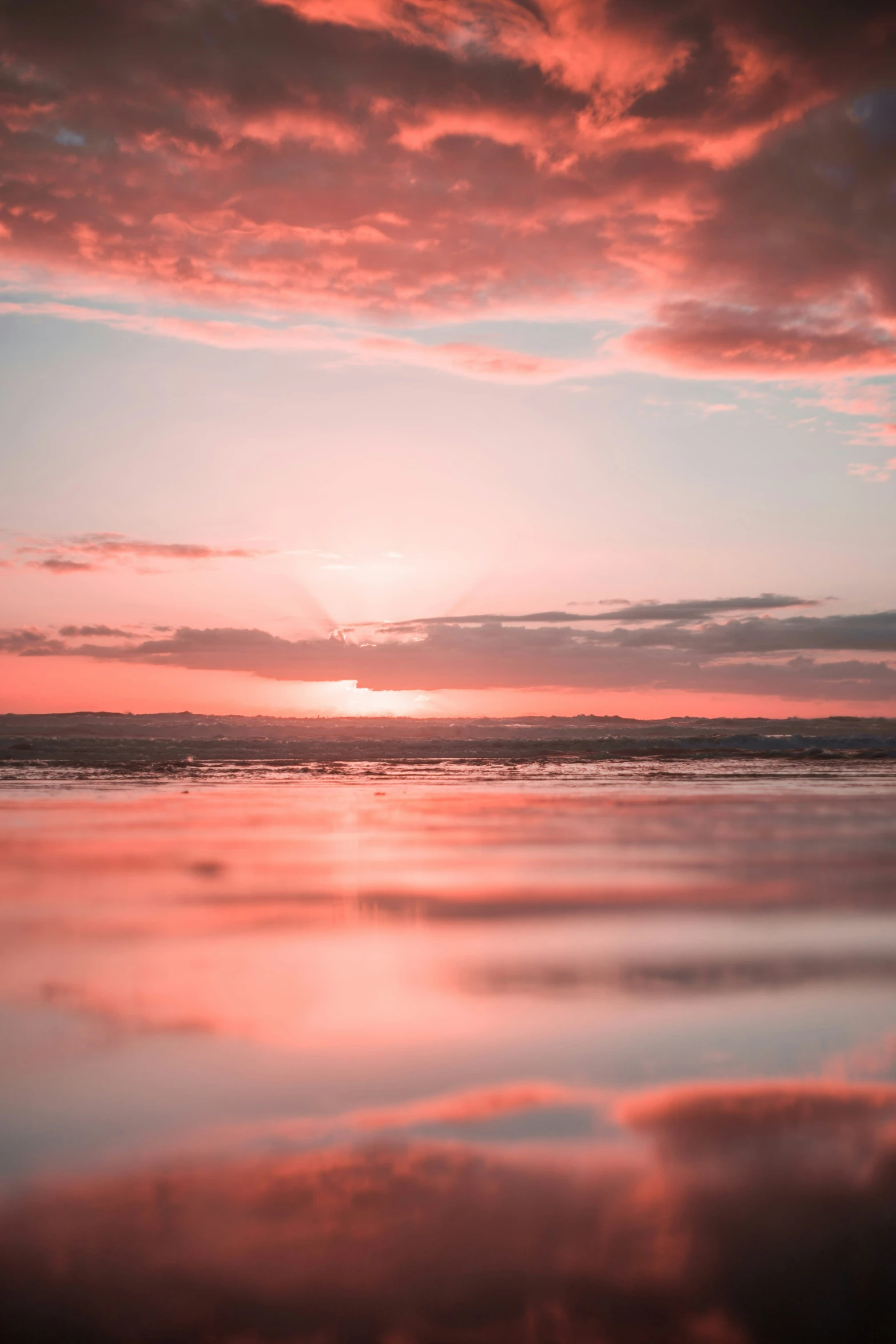 the sun is setting over the ocean in the water