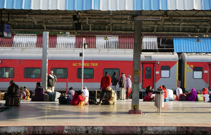 some people sitting and standing around with their luggage in hand