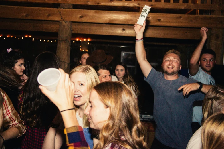 a crowd of people standing around each other holding up cups