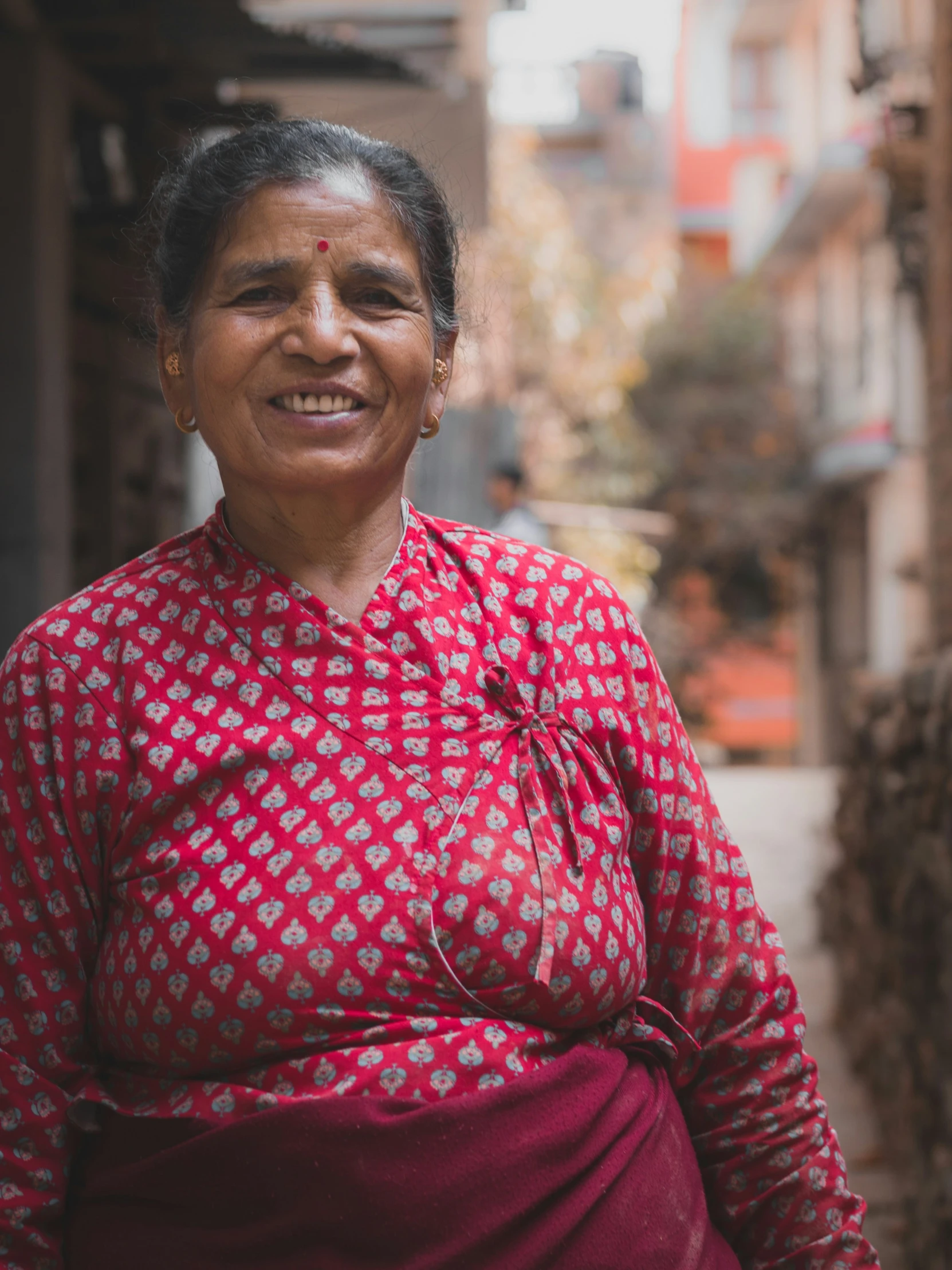 a woman with black hair is smiling and standing in the alley