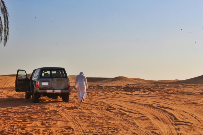 man in a white outfit walking next to a truck