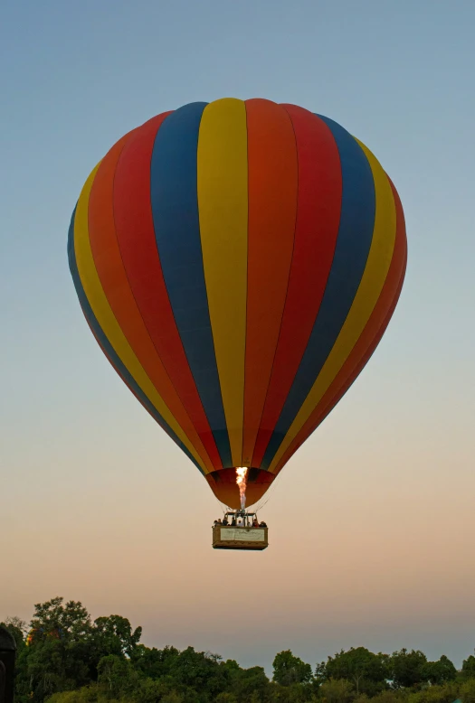 a rainbow colored  air balloon is soaring above the grass