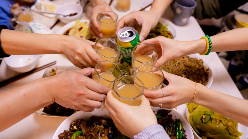 some people are holding beverages over a white table