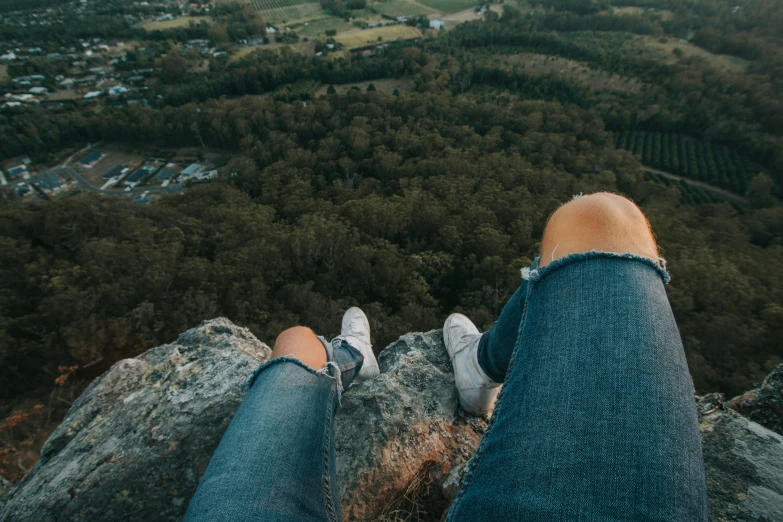 person on top of rock looking at lush landscape