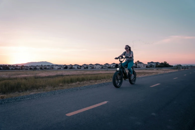 a woman riding her motor bike down the road at dusk