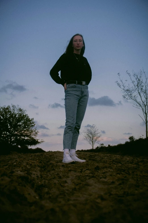 a man standing in the dirt while wearing jeans