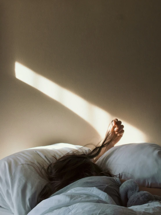 a woman laying on a bed under a white sheet