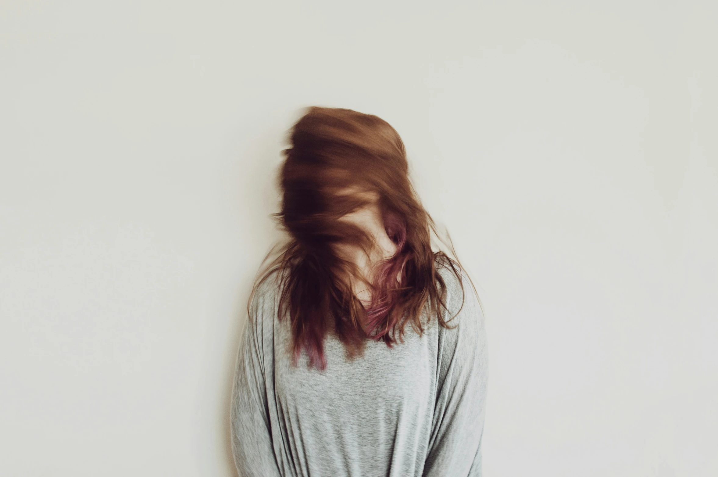 a woman with long hair in front of a white wall