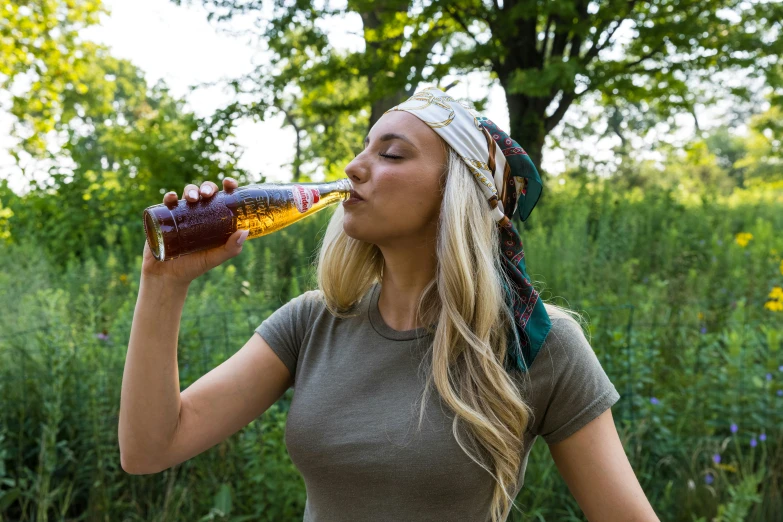 woman drinking soda sitting outdoors near green grass