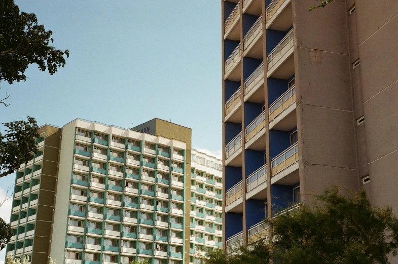 two tall buildings standing next to each other near a tree