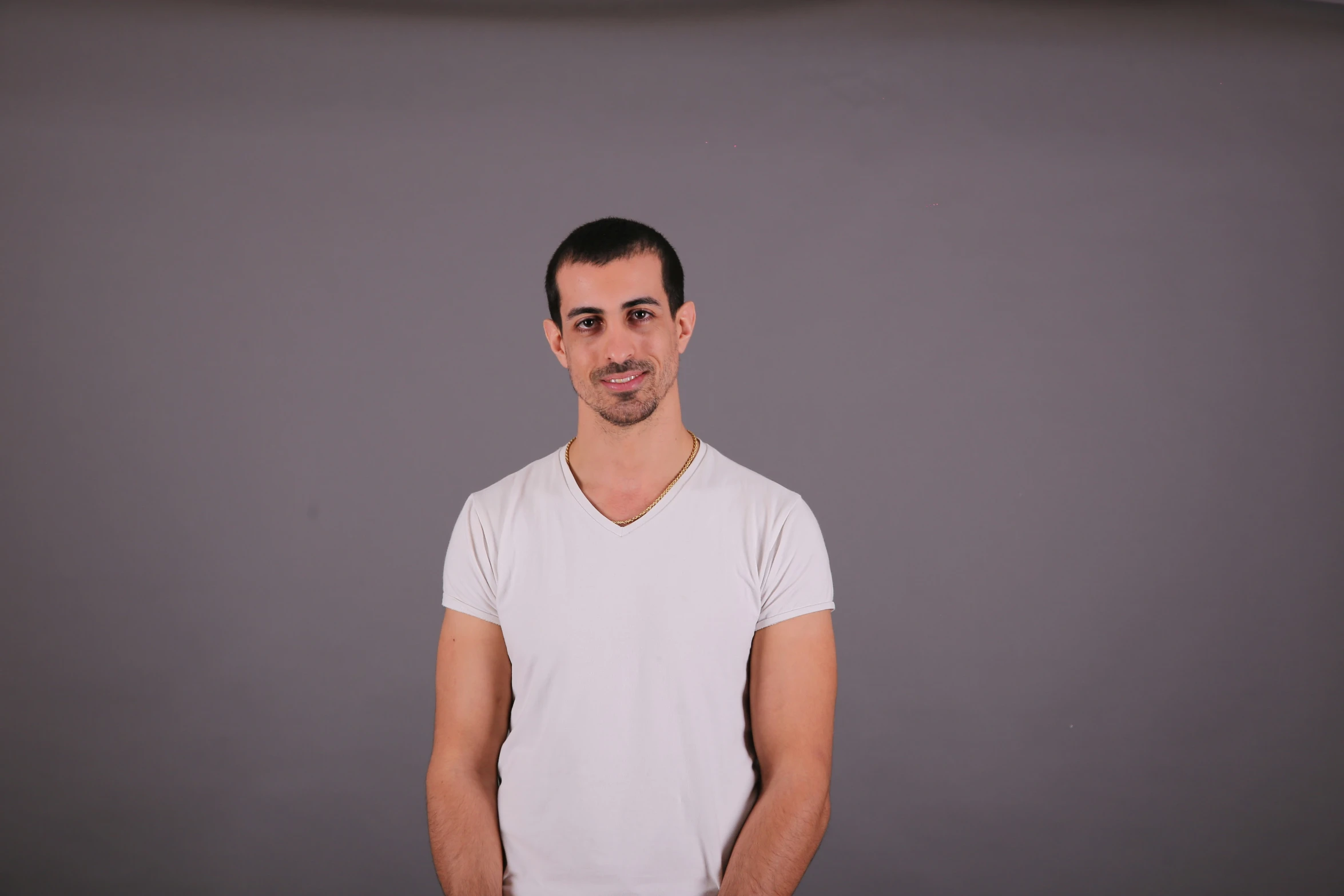 man wearing white t - shirt and smiling with grey background