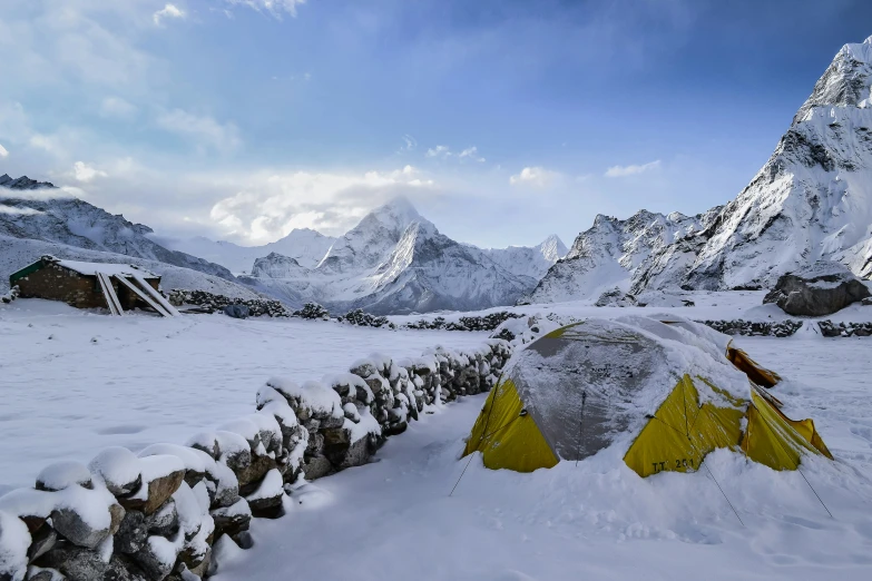 a stone fence with an orange tents on it in the snow