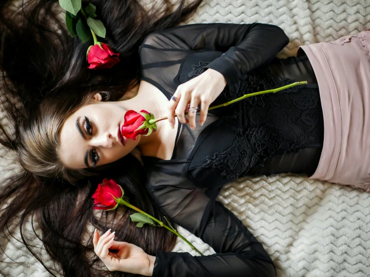 a woman laying down on a bed with a rose