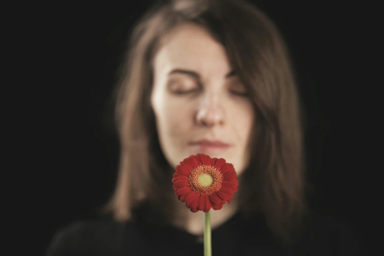 a woman holding a flower with her eyes closed