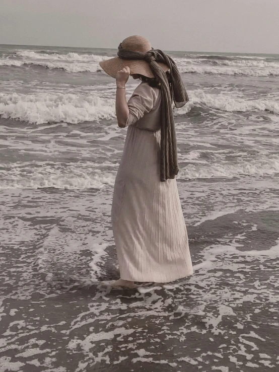 woman in dress and hat walking along the beach