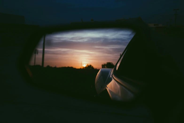 the sun is shown behind a rear view mirror