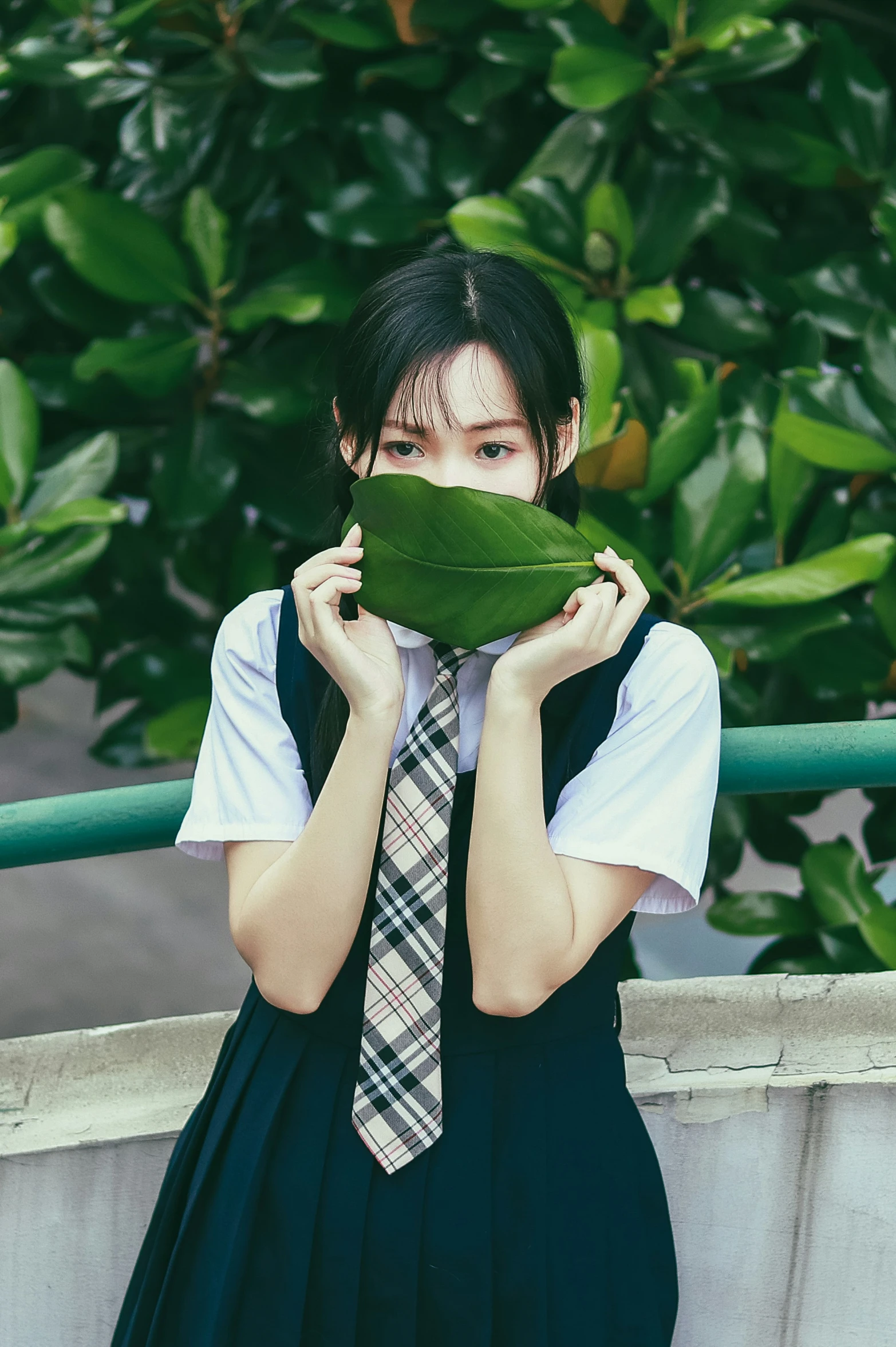 a girl in school dress with tie and a leaf behind her