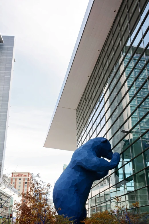 a giant blue bear statue outside of a glass building