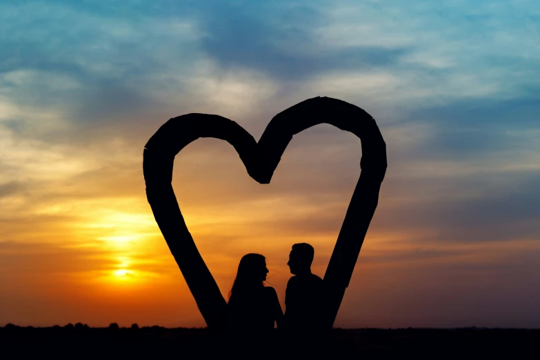 two people are silhouetted in front of a heart - shaped heart