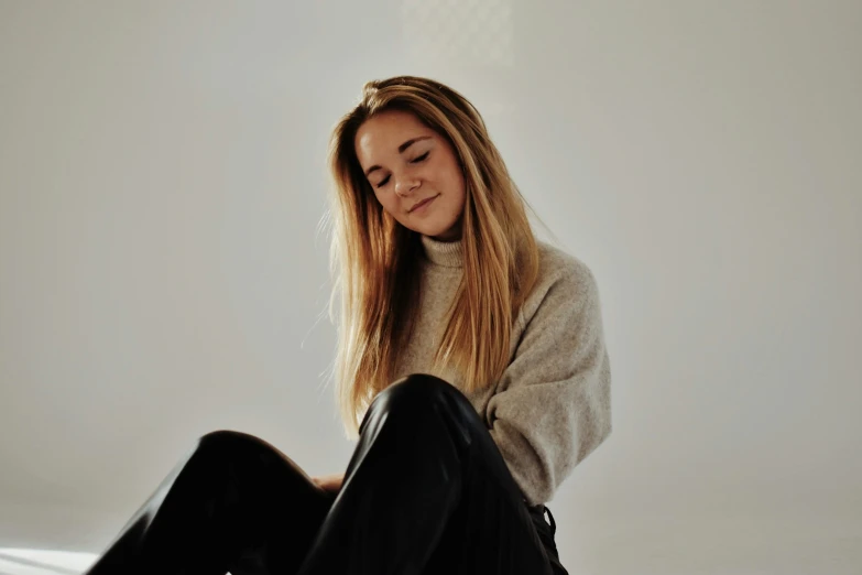 a young woman sitting down on the floor looking to her side