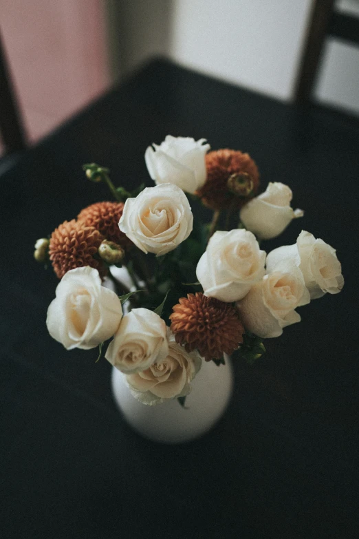 white roses are in a white vase on a table