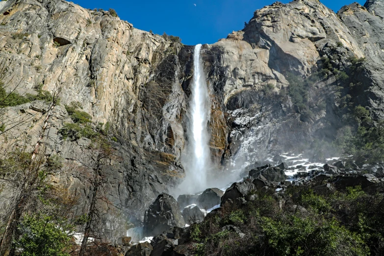 waterfall in a mountain with trees under clear sky