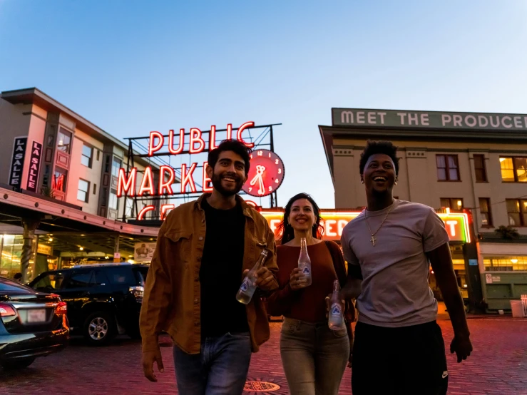 three people walking down the street holding beverages